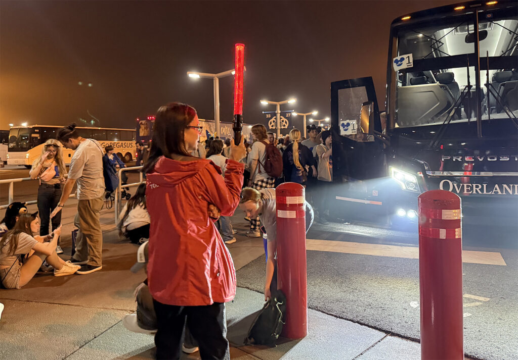 A SBNYC tour guide leading a bus in the parking lot late at night in Orlando.